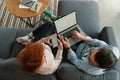 Top view of family couple resting on comfy couch having fun using laptop and phone Royalty Free Stock Photo