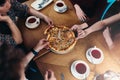 Top view of family members having lunch reaching out for pizza pieces in pizzeria