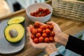 Top view farmer female hands holding bowl with small ripe cherry tomatoes and fresh green avocado Royalty Free Stock Photo