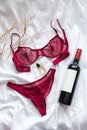 Top view fashion red lace lingerie with bootle of red wine and perfume. Set of woman essential accessory and underwear