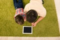 Top view of father and son lying on green carpet with tablet