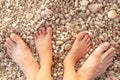 Top view the feet of adult and a child on the gravel pebble beach. Father and daughter love. Flat design, summer holidays creative Royalty Free Stock Photo