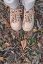 Top view of feet in beige lace-up shoes standing on fallen autumn leaves Royalty Free Stock Photo