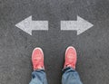 Top view of feet and different direction arrows on asphalt road