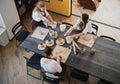 Top view of female artists sculpting different clay products on a big wooden table with pottery tools on it during a