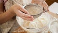 Top view of female baker sifting flour with sieve in big glass bowl for making dough. Royalty Free Stock Photo