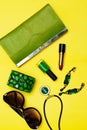 Top view of female fashion accessories . Green handbag with lipstick bracelet earnings necklace