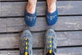 Ffemale feet wearing slippers and male feet wearing cycling shoes standing on an old wooden floor Royalty Free Stock Photo