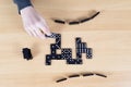 Top View Of Female Hand And Black Dominoes On Wooden Board