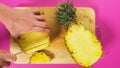 Top view, female hand cuts the fruit with a knife on a wooden board, pineapple. The concept of natural healthy food.