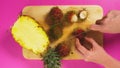 Top view, female hand cuts fruits with a knife on a wooden board, pineapple and rambutan. The concept of natural healthy