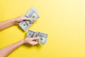 Top view of female hand giving some money, Close-up of counting one hundred dollar bills. Business concept on colorful background