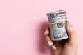 Top view of female hand holding a pack of rolled money on colorful background. One hundred dollars. Business concept with empty Royalty Free Stock Photo