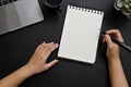 Top view, A female hand holding pen, taking notes on spiral notepad in her modern black desk Royalty Free Stock Photo