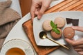 Female hand picking  French macarons from a plate on coffee table with tea cup Royalty Free Stock Photo