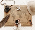 Top view of female hands hold cup of black coffee over vintage world map with traveler accessories Royalty Free Stock Photo