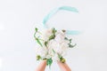 Top view female hands holding beautiful white peony bouquet with satin ribbon on light background. Wedding concept. Bride flowers. Royalty Free Stock Photo