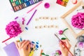 Top view Female Hands holding brush with Create beauty lettering, colorful painting materials and peony flowers on white Royalty Free Stock Photo