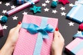 Top view of female hands holding a Christmas present on festive black background. Holiday decorations, toys and balls. New Year Royalty Free Stock Photo