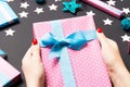 Top view of female hands holding a Christmas present on festive black background. Holiday decorations, toys and balls Royalty Free Stock Photo