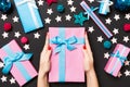 Top view of female hands holding a Christmas present on festive black background. Holiday decorations, toys and balls Royalty Free Stock Photo