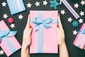 Top view of female hands holding a Christmas present on festive black background. Holiday decorations, toys and balls. New Year Royalty Free Stock Photo