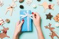 Top view of female hands holding a Christmas present on festive blue background. Holiday decorations and toys. New Year Royalty Free Stock Photo