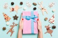 Top view of female hands holding a Christmas present on festive blue background. Holiday decorations and toys. New Year holiday Royalty Free Stock Photo