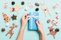 Top view of female hands holding a Christmas present on festive blue background. Holiday decorations and toys. New Year holiday Royalty Free Stock Photo