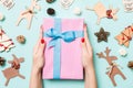 Top view of female hands holding a Christmas present on festive blue background. Holiday decorations and toys. New Year holiday Royalty Free Stock Photo