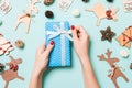 Top view of female hands holding a Christmas present on festive blue background. Holiday decorations and toys. New Year holiday Royalty Free Stock Photo