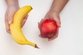 Top view of female hands holding and comparing between red apple and banana isolated on white Royalty Free Stock Photo