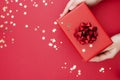 Top view of female hands holding gift box with red ribbon bow isolated over flat lay background, copy space Royalty Free Stock Photo