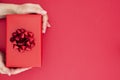 Top view of female hands holding gift box with red ribbon bow  over flat lay background, copy space Royalty Free Stock Photo