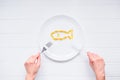 Top view female hands holding knife and fork under round plate with Cod Liver Oil Capsules, Omega 3, Vitamin D in the fish shape o Royalty Free Stock Photo