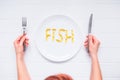 Top view female hands holding knife and fork under round plate with Fish word lettering by cod Liver Oil Capsules, Omega 3 on the Royalty Free Stock Photo