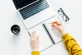 Top view of female hands holding pencil at table with laptop, eyeglasses and cup of coffee Royalty Free Stock Photo