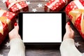 Top view of female hands holding a tablet on wooden Christmas background made of gift boxes and snowflakes. New year holiday Royalty Free Stock Photo