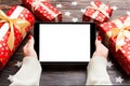 Top view of female hands holding a tablet on wooden Christmas background made of gift boxes and snowflakes. New year holiday Royalty Free Stock Photo