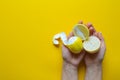 Top view of female hands holding whole and sliced ripe lemons on a yellow surface, concept of health and vitamins Royalty Free Stock Photo