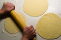 Top view of female hands kneading dough with wooden rolling pin
