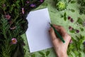 Top view of female handwriting on a blank white paper with a green pen on a green tabletop