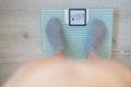 Top view on female legs in gray socks on electronic scales. Very heavy weight. The surprise of the increase in kg on a