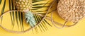 Top view female traveler accessories on yellow background. Flat lay rattan straw bag, pineapple, palm leaf. Summer fashion,