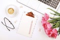 Top view of female worker desktop with laptop, flowers and different office supplies items. Feminine creative design workspace.