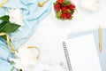 Top view feminine desk workspace with peony flowers, blank paper notepad, bowl of strawberries. Flat lay style composition with Royalty Free Stock Photo