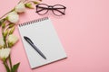 Feminine workplace with jotter, eyeglasses and flowers in pastel Royalty Free Stock Photo