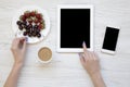 Top view, feminine workspace with female hands, smartphone, tablet, berries and latte on white wooden background. Flat lay. Royalty Free Stock Photo