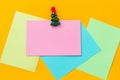 festive christmas clothespin and empty paper sheets with free space for text on a vibrant yellow background