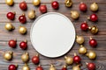 Top view of festive plate with red and golden baubles on wooden background. Christmas decorations and toys. New Year advent Royalty Free Stock Photo